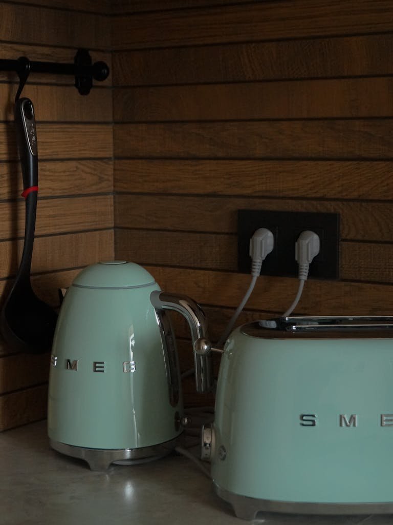 Pastel green electric kettle and toaster set against wooden kitchen decor.